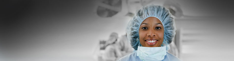 Header photo showing smiling nurse in front of operating theatre 